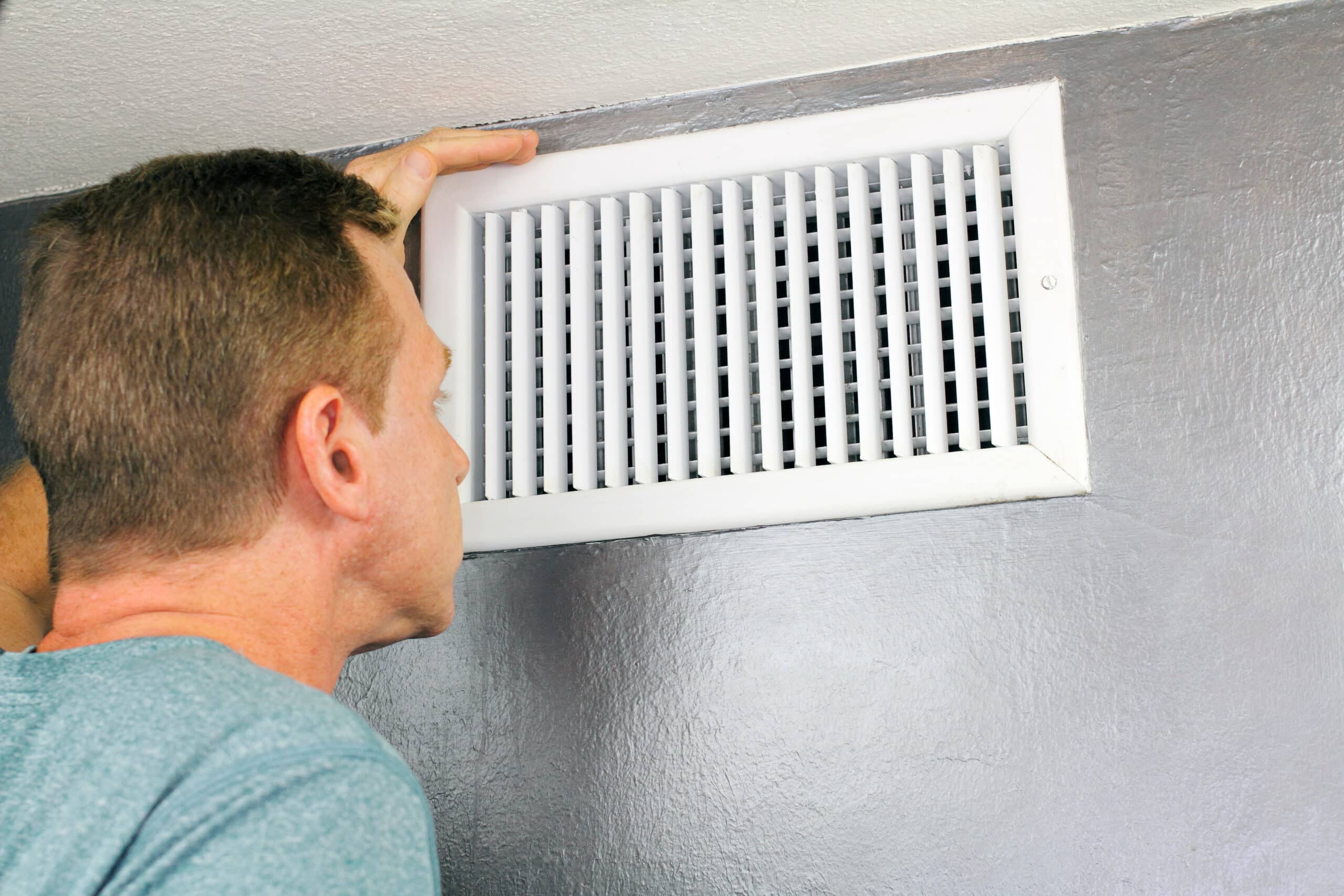Man looking at air vent inside of home in Colorado Springs, CO.