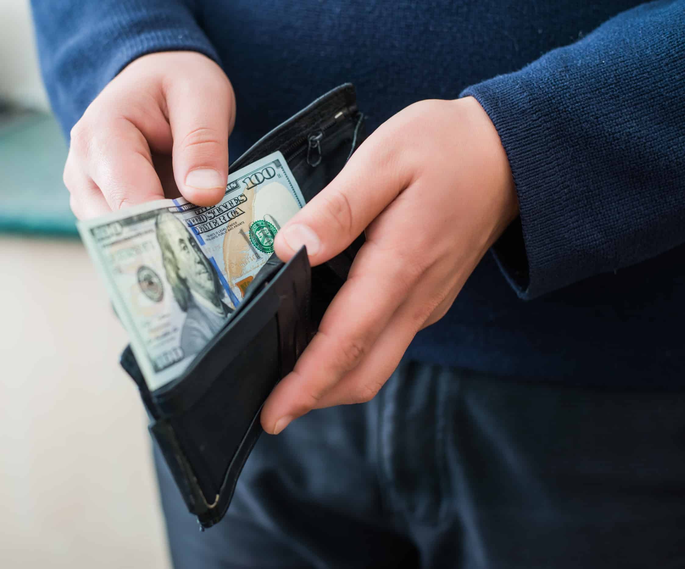 hands in wallet with hundred dollar bill.
