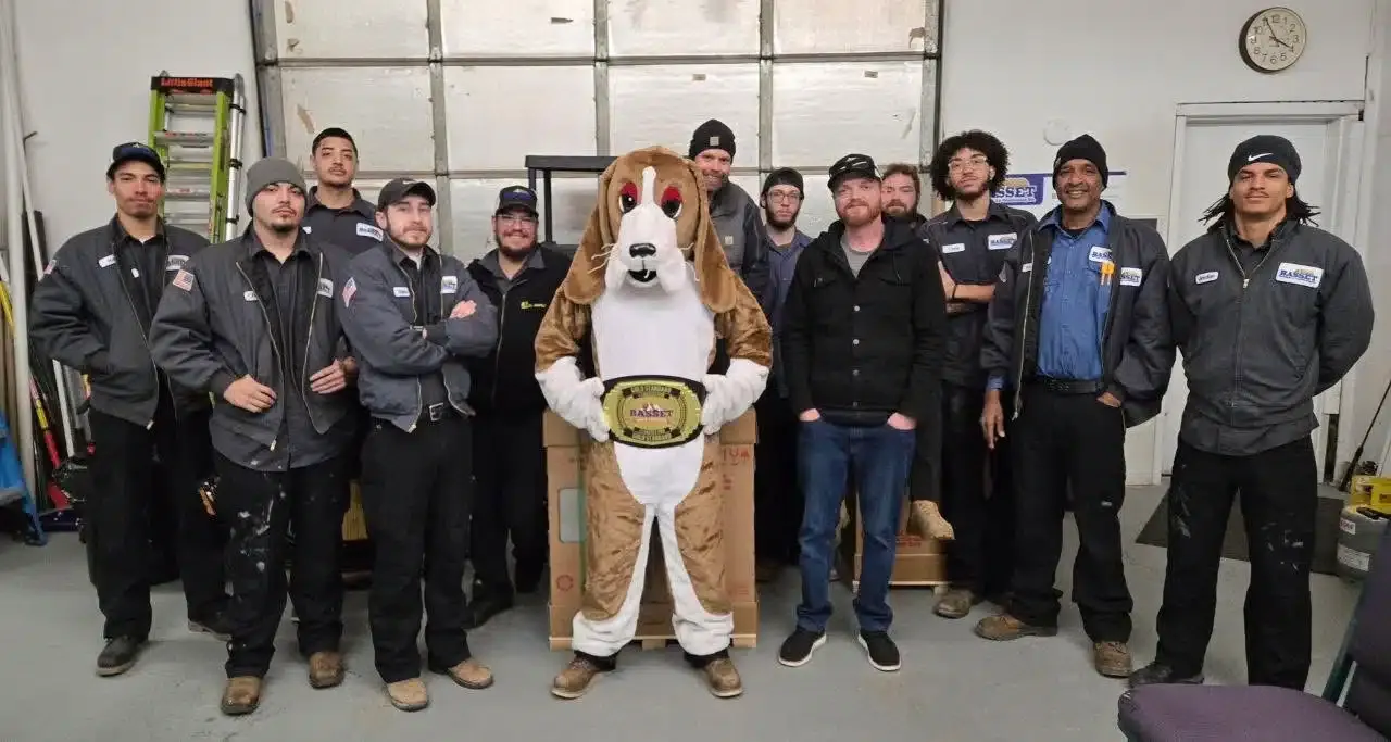 Team of BASSETT plumbing and heating technicians with basset hound mascot at Colorado Springs company headquarters